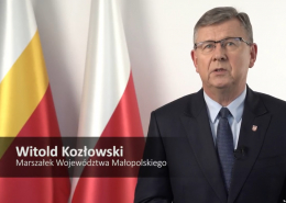 Marszałek Województwa Małopolskiego Witold Kozłowski na tle flag