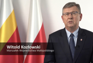 Marszałek Województwa Małopolskiego Witold Kozłowski na tle flag