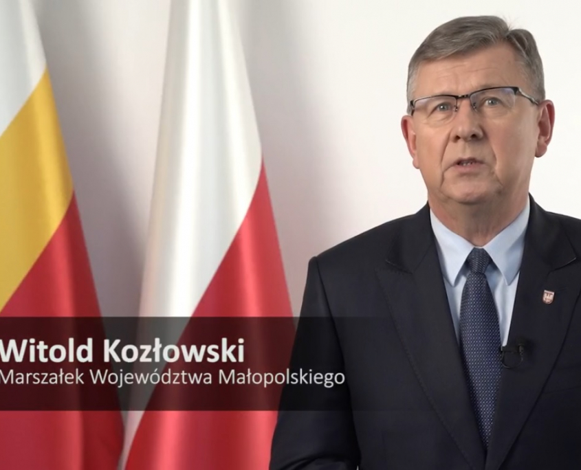 Marszałek Województwa Małopolskiego Witold Kozłowski na tle flag