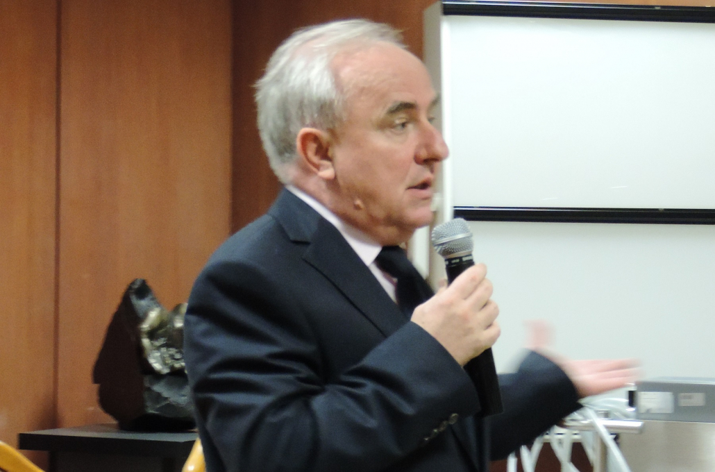 Na zdjęciu kolorowym prof. Rafał Drwiła z mikrofonem, przemawia