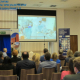 Ekran z wyswietalnym filmem podczas konferencji i słuchacze