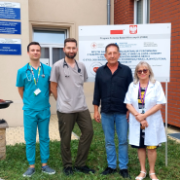Cztery osoby pozujące przed budynkiem M-8 na tle tablicy informującej o projekcie CRACOVIA-HF.