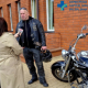 Mężczyzna pod szpitalnym budynkiem przy motocyklu rozmawiający z redaktorem z telewizji.