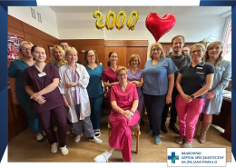 Na fotografii przedstawiono grupę lekarzy, fizjoterapeutów i psychologów wschodzacych w skład poradni prehabilitacyjnej w naszym szpitalu. W tle umieszczono 4 balony. 4 z nich układają się w liczbę 2000, ostani ma kształt serca. Całość odnosi się do 2000 pacjentów przyjętych w poradni w niecałe dwa lata.
