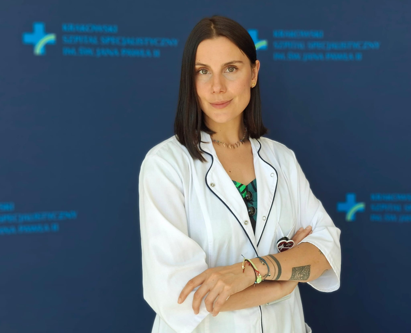 Psycholog M. Sankiewicz na tle szpitalnych logotypów.