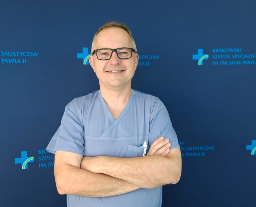 Dr M. Stąpór na tle szpitalnych logotypów.