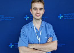 mgr Miłosz Wujek w medycznym ubraniu na granatowym tle