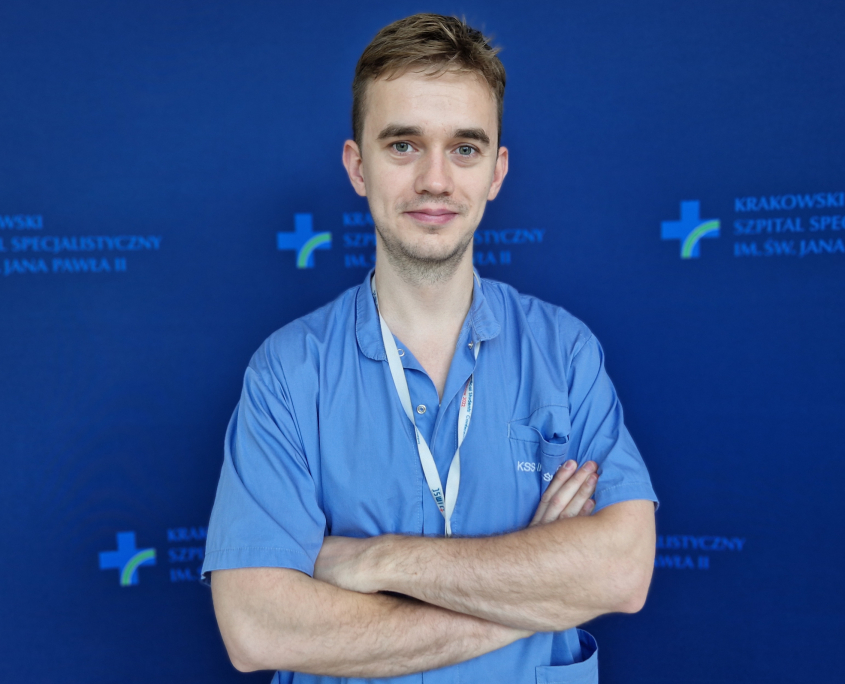 mgr Miłosz Wujek w medycznym ubraniu na granatowym tle