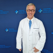 prof. dr hab. n. med. Grzegorz Gajos w medycznym ubraniu na granatowym tle