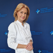 Prof. dr hab. n. med. Ewa Konduracka w medycznym ubraniu na granatowym tle