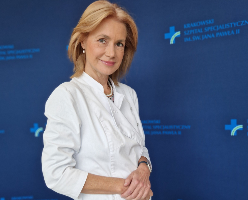 Prof. dr hab. n. med. Ewa Konduracka w medycznym ubraniu na granatowym tle