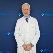 Dr hab. n. med. Andrzej Gackowski w stroju medycznym na granatowym tle