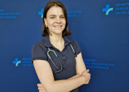 dr n. med. Ewa Dziewięcka na grantowym tle w stroju medycznym