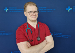 lek. Mateusz Winiarczyk na granatowym tle w medycznym ubraniu