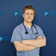 lek. Łukasz Wilczek w medycznym ubraniu na granatowym tle