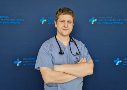 lek. Łukasz Wilczek w medycznym ubraniu na granatowym tle