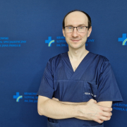 dr n. med. Wojciech Magoń w medyczny ubraniu na granatowym tle