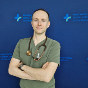 lek. Michał Surdacki w medycznym ubraniu na granatowym tle