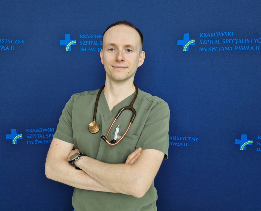 lek. Michał Surdacki w medycznym ubraniu na granatowym tle