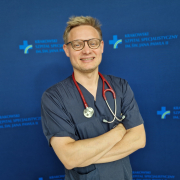 dr n. med. Jakub Stępniewski w medycznym ubraniu na granatowym tle