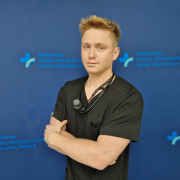 lek. Michał Tworek w medycznym ubraniu na grantowym tle