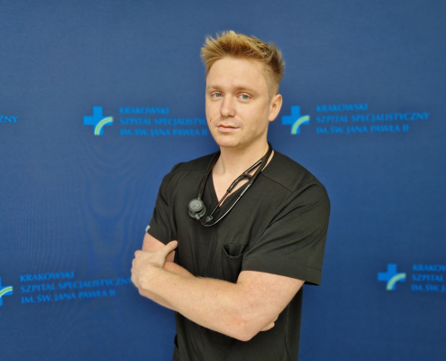 lek. Michał Tworek w medycznym ubraniu na grantowym tle