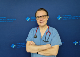 prof. dr hab. n. med. Paweł Rubiś w medycznym ubraniu na grantowym tle