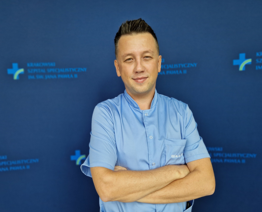 mgr Tomasz Sprzyp w medycznym ubraniu na granatowym tle