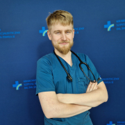 lek. kacper milcznowski w medycznym ubraniu na granatowym tle