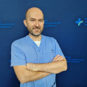 dr n. med. Daniel Rzeźnik w medycznym ubraniu na granatowym tle