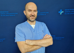 dr n. med. Daniel Rzeźnik w medycznym ubraniu na granatowym tle