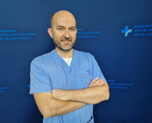 dr n. med. Daniel Rzeźnik w medycznym ubraniu na granatowym tle