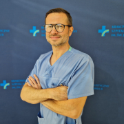 dr n. med. Łukasz Tekieli w medycznym ubraniu na granatowym tle