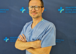 dr n. med. Łukasz Tekieli w medycznym ubraniu na granatowym tle