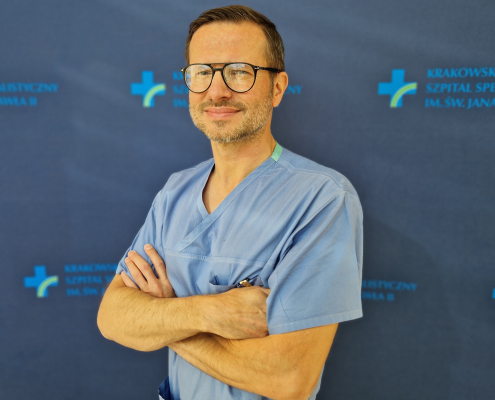 dr n. med. Łukasz Tekieli w medycznym ubraniu na granatowym tle