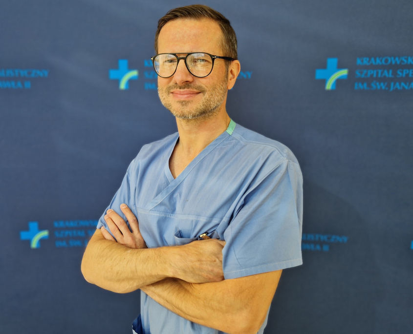 dr n. med. Łukasz Tekieli w medycznym ubraniu na granatowym tle