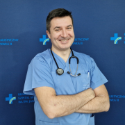 Lek. Paweł Prochownik w medycznym ubraniu na granatowym tle