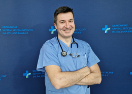 Lek. Paweł Prochownik w medycznym ubraniu na granatowym tle