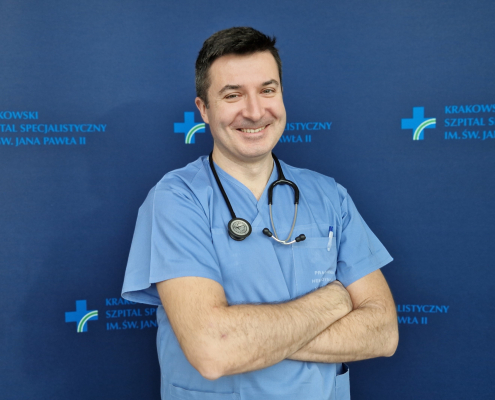 Lek. Paweł Prochownik w medycznym ubraniu na granatowym tle