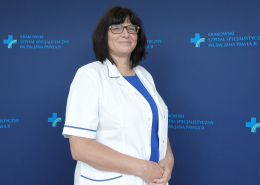 Lek. Marta Węgrzynowska w medycznym ubraniu na granatowym tle