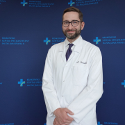 Dr hab. n. med. Aleksander Siniarski w medycznym ubraniu na granatowym tle