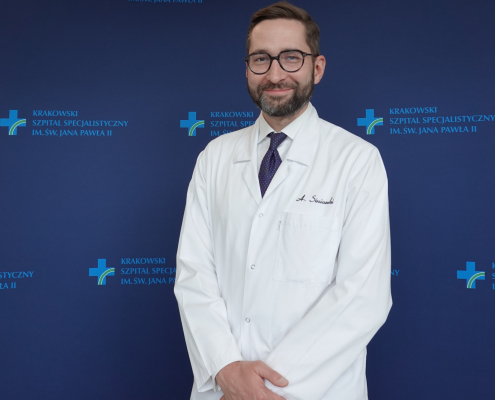 Dr hab. n. med. Aleksander Siniarski w medycznym ubraniu na granatowym tle