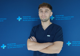 lek. Mateusz Stec w medycznym ubraniu na granatowym tle