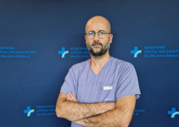 Lek. Krzysztof Karwat w medycznym ubraniu na granatowym tle