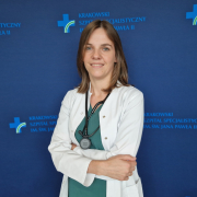 lek. Małgorzata Pińska w medycznym ubraniu na granatowej ściance