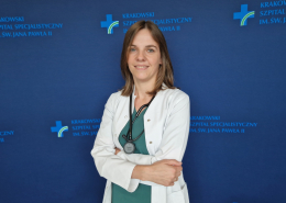 lek. Małgorzata Pińska w medycznym ubraniu na granatowej ściance