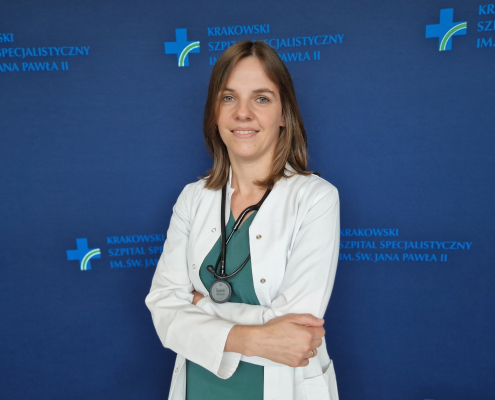 lek. Małgorzata Pińska w medycznym ubraniu na granatowej ściance