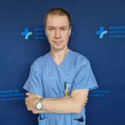 dr med. Mateusz Wnuk w medycznym ubraniu na granatowym tle