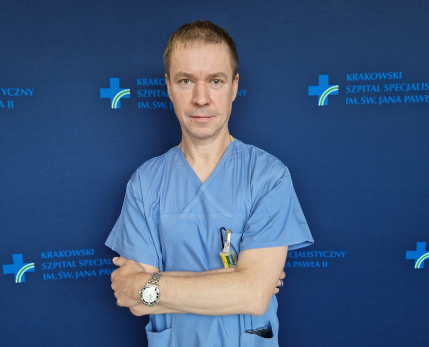 dr med. Mateusz Wnuk w medycznym ubraniu na granatowym tle