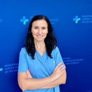 Dr n. med. Sylwia Wiśniowska-Śmiałek w medycznym ubraniu na granatowym tle